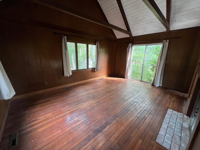 spare room with lofted ceiling with beams, dark wood-type flooring, and wooden walls