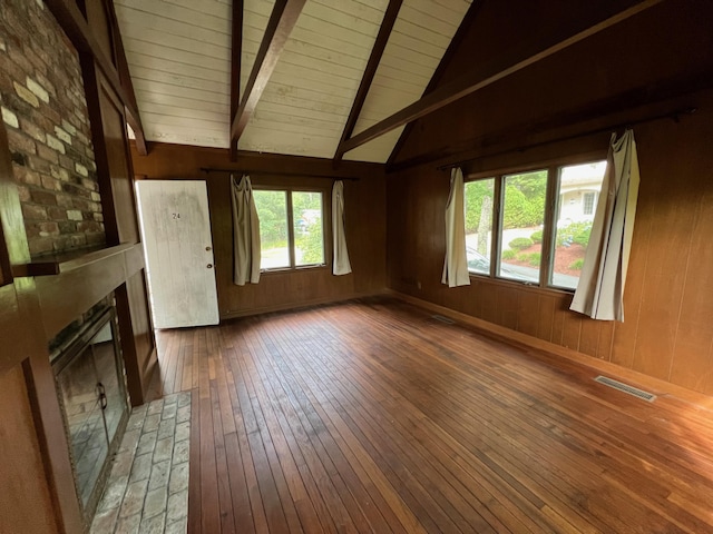 unfurnished living room with a fireplace, dark wood-type flooring, wooden ceiling, and wooden walls