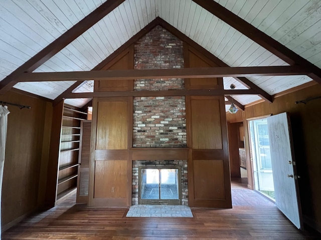 unfurnished living room featuring dark wood-type flooring, beam ceiling, a fireplace, high vaulted ceiling, and wood walls