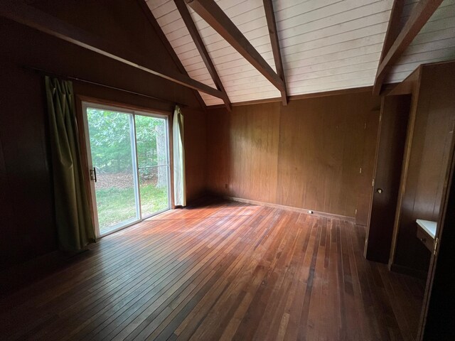 unfurnished living room featuring dark hardwood / wood-style floors, wood walls, and lofted ceiling with beams