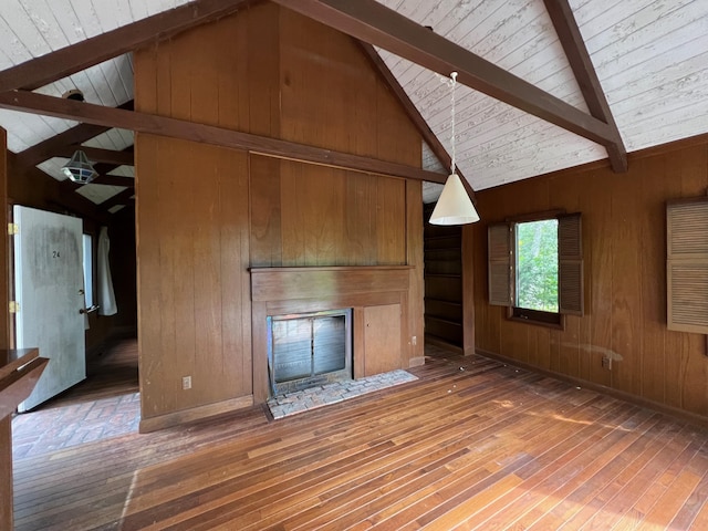 unfurnished living room featuring high vaulted ceiling, wood-type flooring, beamed ceiling, and wooden walls