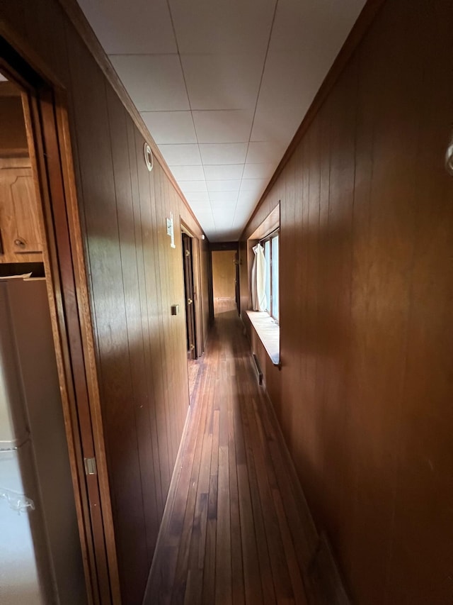 hall with wood walls, hardwood / wood-style floors, and crown molding