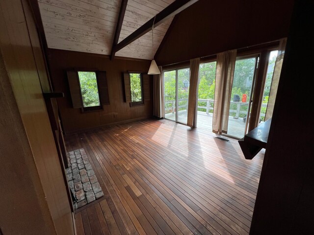 interior space featuring lofted ceiling with beams, wooden ceiling, wood-type flooring, and wooden walls