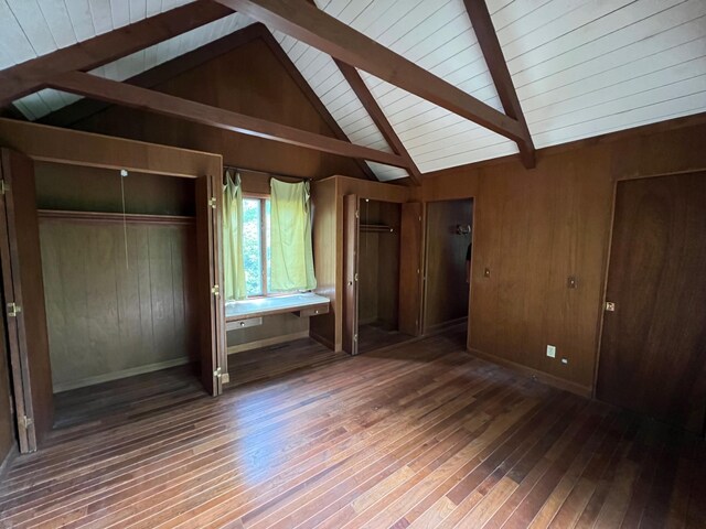 unfurnished bedroom featuring wood-type flooring, wood walls, and lofted ceiling with beams