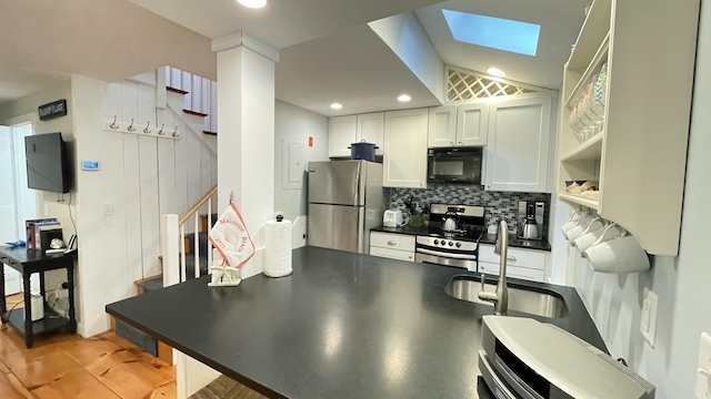 40 Brant Rock Rd, Mashpee, MA 02649 - kitchen featuring appliances with stainless steel finishes, dark countertops, decorative backsplash, white cabinets, and a skylight