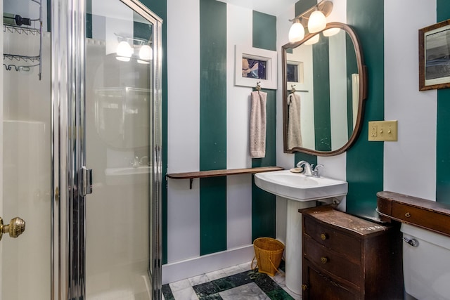 bathroom with a shower stall, toilet, and baseboards