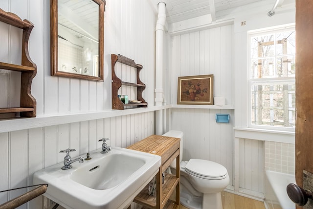 full bathroom with toilet, a tub, and a sink