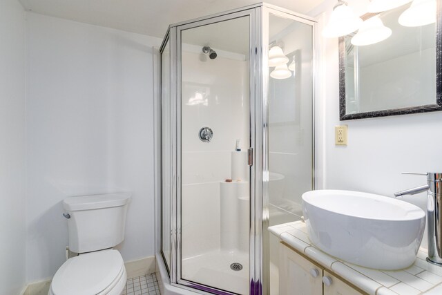 bathroom featuring toilet, a stall shower, and vanity