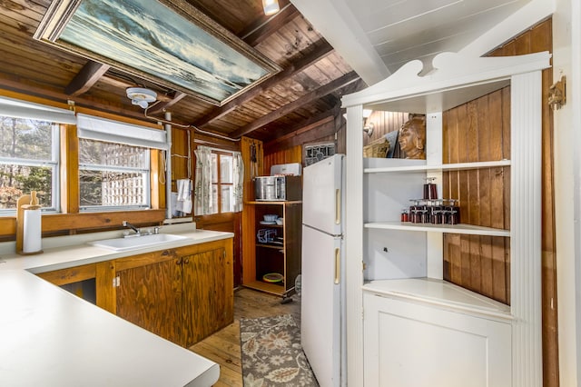 kitchen featuring light countertops, lofted ceiling with beams, a sink, wood finished floors, and wooden ceiling