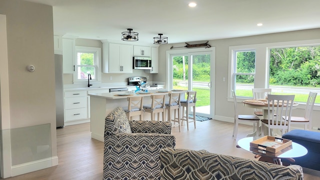 2-A Bodfish Ave, Sandwich, MA 02563 - kitchen with stainless steel microwave, light wood-type flooring, light countertops, stove, and white cabinets