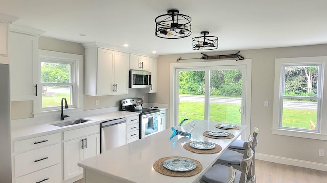 2-A Bodfish Ave, Sandwich, MA 02563 - kitchen featuring stainless steel appliances, light countertops, a breakfast bar, light wood-type flooring, and white cabinetry