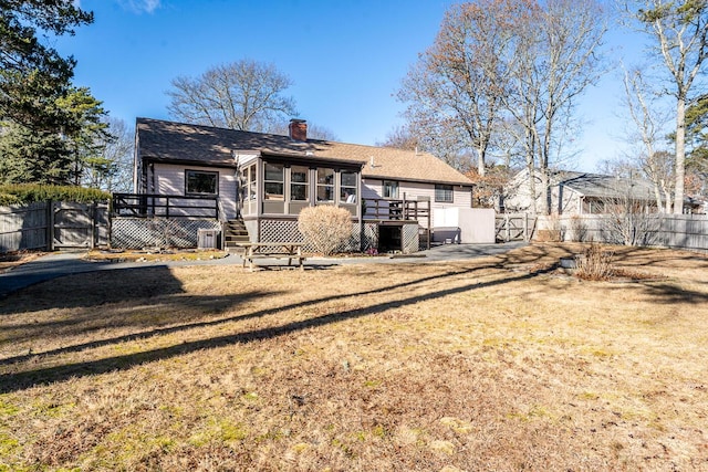 rear view of house featuring a yard, a deck, and a sunroom