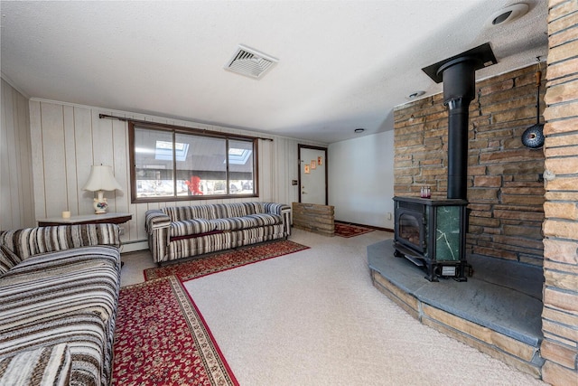 living room with a textured ceiling, baseboard heating, and a wood stove