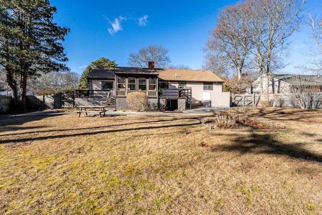 back of house featuring a sunroom, a deck, and a lawn