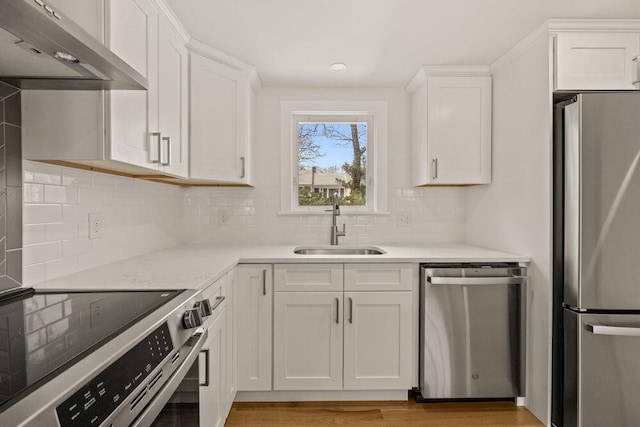 kitchen with under cabinet range hood, stainless steel appliances, white cabinetry, and a sink