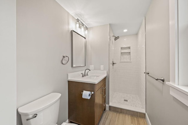 full bath featuring wood finished floors, vanity, toilet, recessed lighting, and tiled shower