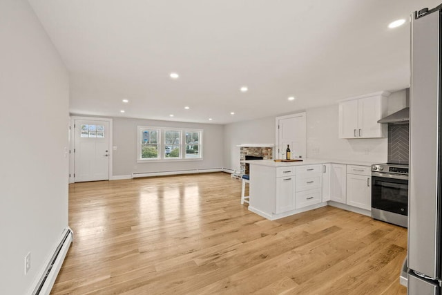 kitchen with open floor plan, stainless steel range with electric stovetop, a baseboard heating unit, and white cabinetry