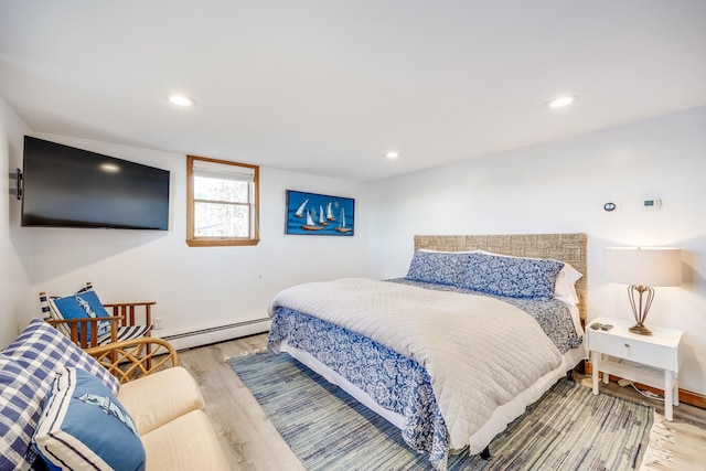 bedroom featuring light wood finished floors, a baseboard heating unit, and recessed lighting