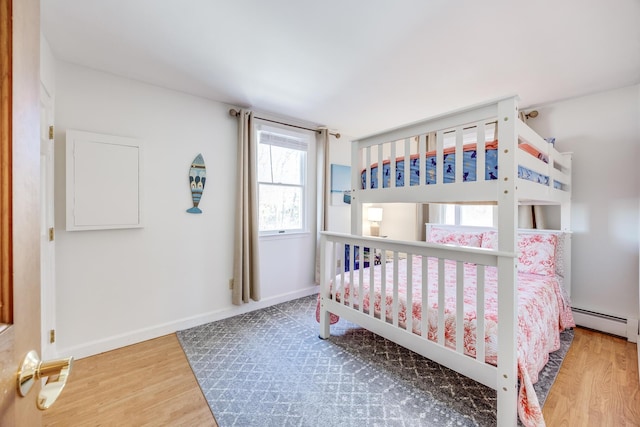 bedroom with a baseboard radiator, baseboards, and wood finished floors