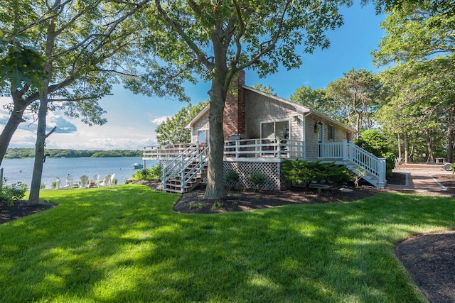 view of side of home featuring a yard, stairway, a chimney, and a deck with water view