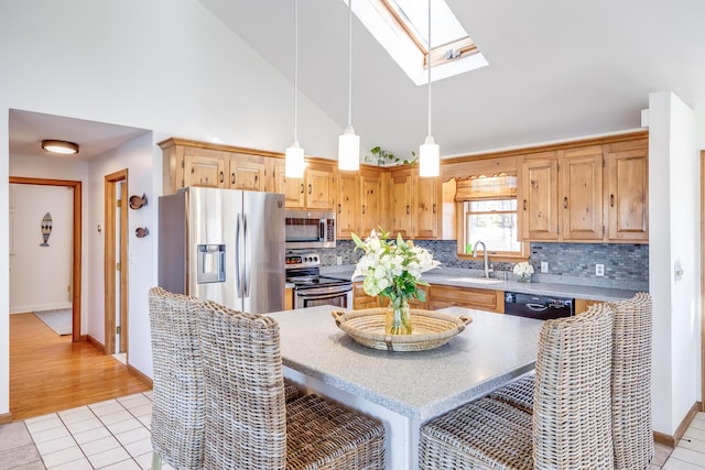 kitchen featuring a skylight, decorative backsplash, appliances with stainless steel finishes, a sink, and light tile patterned flooring