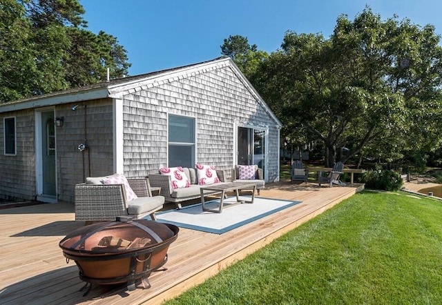 exterior space with a deck, a lawn, and an outdoor living space with a fire pit