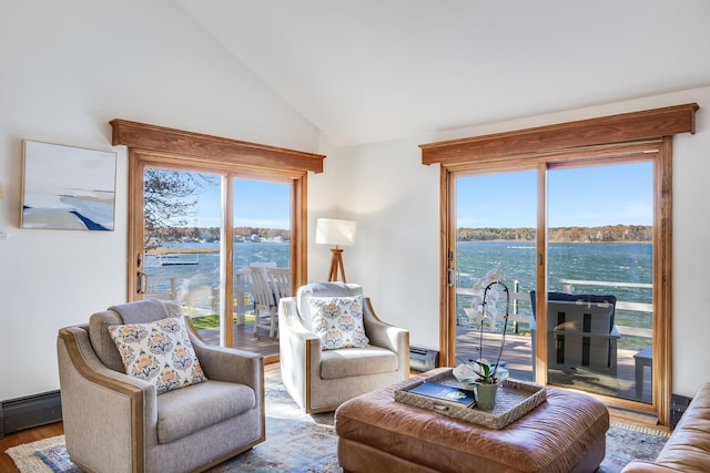 living area with vaulted ceiling, baseboard heating, wood finished floors, and a wealth of natural light