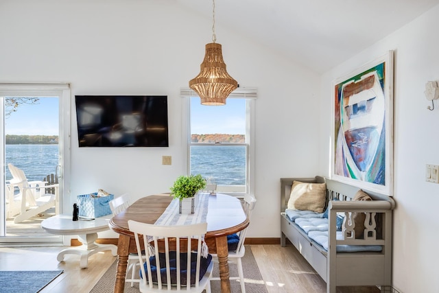 dining room featuring a healthy amount of sunlight, vaulted ceiling, light wood-style flooring, and baseboards