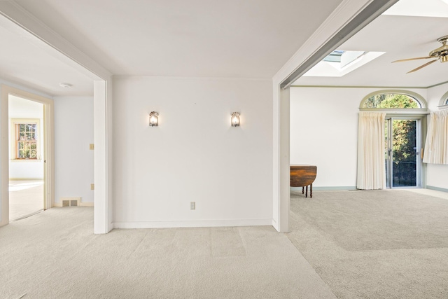 empty room featuring carpet flooring, visible vents, a skylight, and ceiling fan