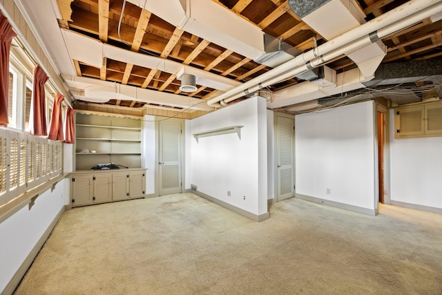 basement featuring light colored carpet and baseboards