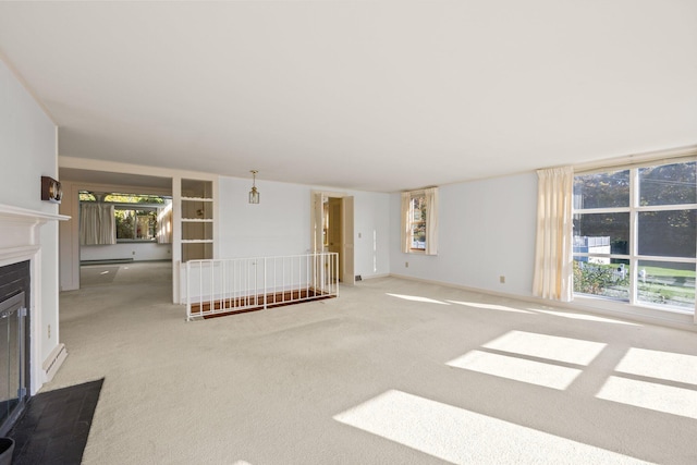 unfurnished living room with baseboards, baseboard heating, a fireplace with flush hearth, and carpet floors