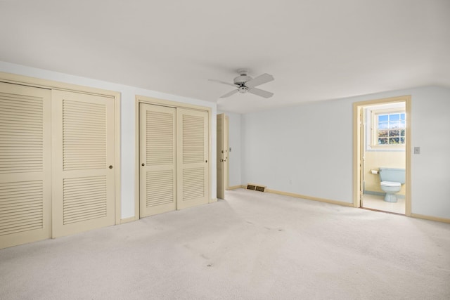 unfurnished bedroom with baseboards, ensuite bathroom, visible vents, multiple closets, and carpet floors