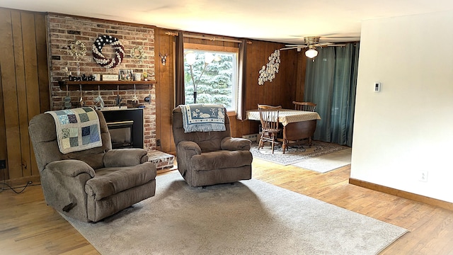 13 Pilgrim Ln, Eastham, MA 02642 - living area featuring baseboards, wood finished floors, wood walls, a brick fireplace, and a ceiling fan