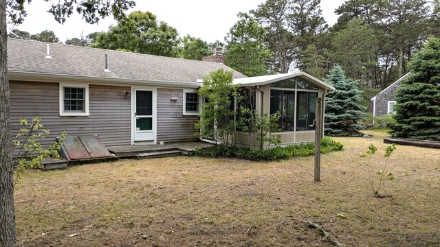 13 Pilgrim Ln, Eastham, MA 02642 - rear view of house featuring a sunroom, a chimney, a yard, and roof with shingles