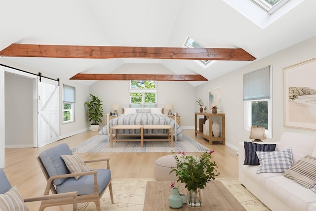 bedroom featuring baseboards, a barn door, vaulted ceiling with skylight, and wood finished floors