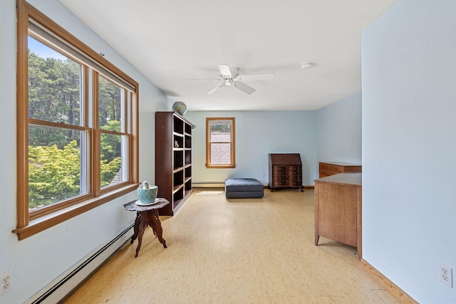 sitting room with a wealth of natural light, light wood-style flooring, ceiling fan, and a baseboard radiator