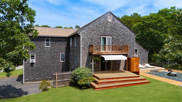 back of property featuring a balcony, a deck, and a yard