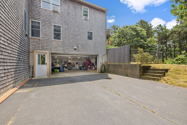 view of home's exterior featuring driveway, a garage, and fence