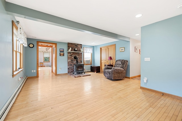 sitting room with hardwood / wood-style floors, baseboards, a wood stove, and baseboard heating