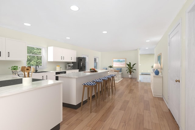 kitchen featuring light countertops, a center island, white cabinets, and light wood finished floors