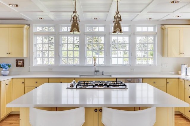 kitchen with a sink, stainless steel gas cooktop, plenty of natural light, beam ceiling, and light countertops