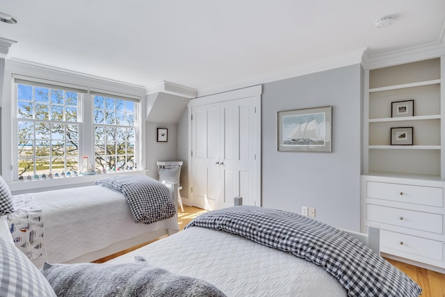bedroom with ornamental molding, light wood finished floors, and a closet