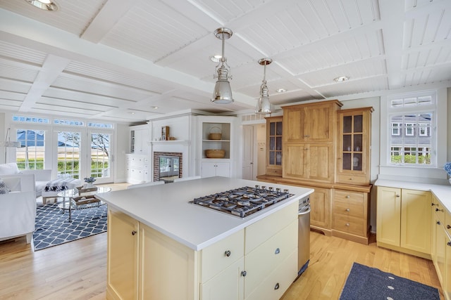 kitchen with gas cooktop, coffered ceiling, light wood-style floors, a kitchen island, and light countertops