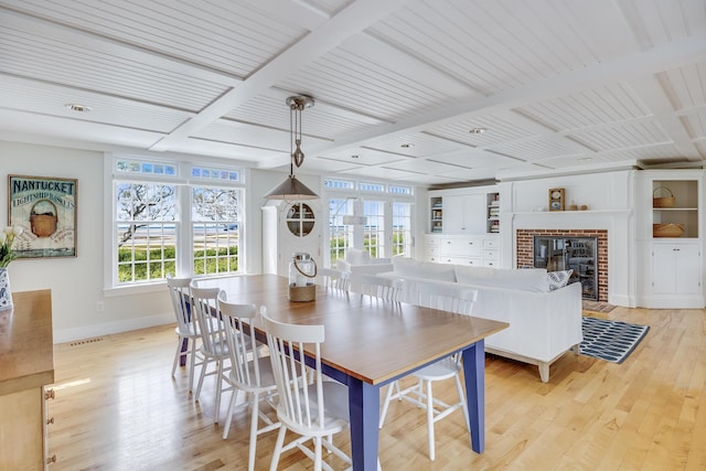 dining room with baseboards, light wood-style flooring, and a fireplace