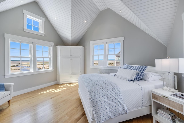bedroom with vaulted ceiling, light wood finished floors, multiple windows, and baseboards