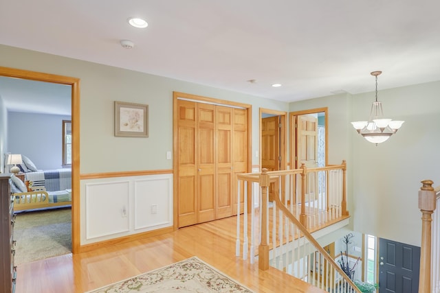 hallway with an inviting chandelier and light hardwood / wood-style floors