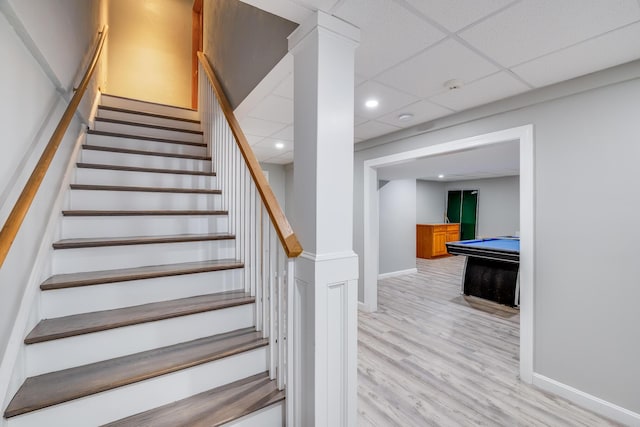 staircase with a drop ceiling and hardwood / wood-style flooring