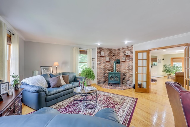 living room with crown molding, a wood stove, light hardwood / wood-style floors, and french doors