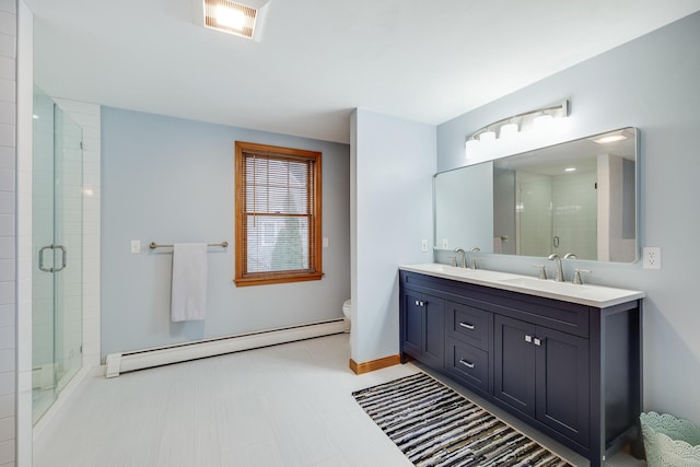 bathroom with vanity, a shower with door, toilet, and baseboard heating