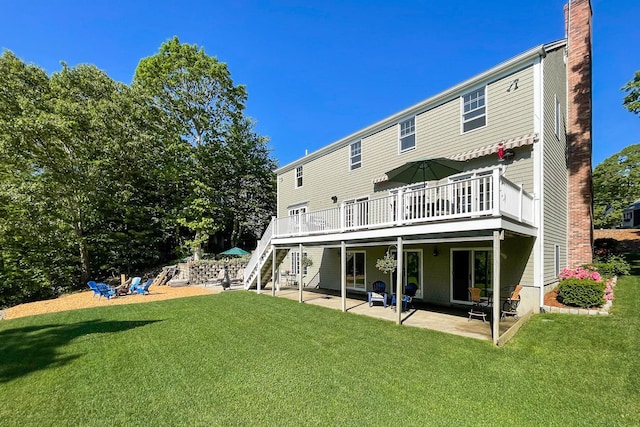 back of property with a wooden deck, a patio area, and a lawn